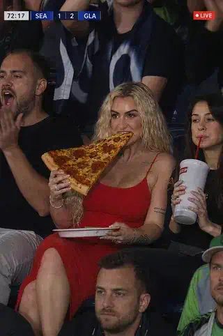 AI stadium video: a fan in the stands bites a huge pizza slice in a mock live TV broadcast